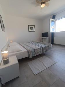 a white bedroom with a bed and a window at Apartments Biba & Lucy in Ražanac