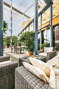 an outdoor patio with wicker chairs and tables at Trans World Hotel Donauwelle in Linz