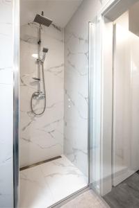 a shower in a bathroom with white marble walls at Apartmány Vulcano in Perná