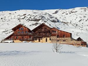 a large wooden building in the snow with a mountain at La Lobio in Molines-en-Queyras