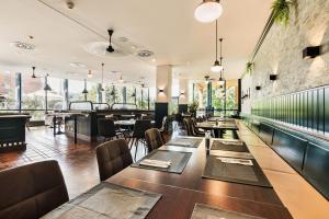 a restaurant with tables and chairs and windows at Trans World Hotel Donauwelle in Linz