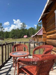a patio with three chairs and a table on a porch at Blue Pearl - Khovsgol Lake in Khyaktil