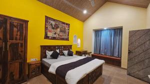 a bedroom with a bed and a yellow wall at Raghuvan Farm in Jaipur