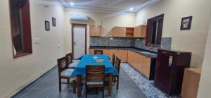 a kitchen with a blue table and wooden chairs at Raghuvan Farm in Jaipur