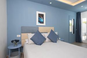 a bedroom with a large white bed with blue walls at Relais Villa Anna in Anacapri