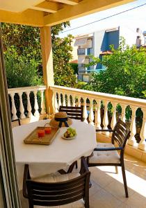 a white table and chairs on a balcony with a table and a bowl of fruit at Eva Maisonette in Iraklitsa