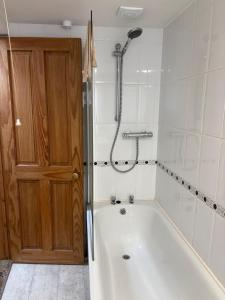 a bathroom with a tub with a shower and a door at Upper Cottage, Brixham in Brixham +26 photos
