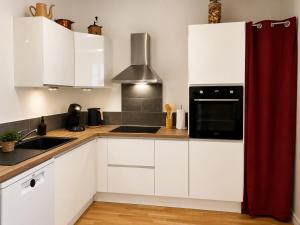 a kitchen with white cabinets and a black microwave at Le Refuge de Mandrin, Elegance et tranquilité in Saint-Genix-sur-Guiers +17 photos