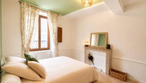a bedroom with a bed with a fireplace and a mirror at Le Refuge de Mandrin, Elegance et tranquilité in Saint-Genix-sur-Guiers