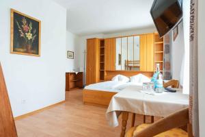 a bedroom with a bed and a table and a television at Strandhotel Pichler in Seeboden