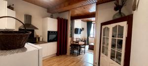 a kitchen with white cabinets and a dining room with a table at Le Refuge de Mandrin, Elegance et tranquilité in Saint-Genix-sur-Guiers