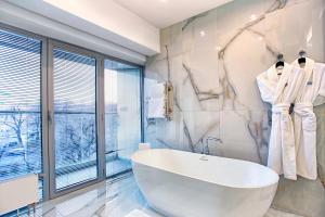 a bathroom with a large white tub and a window at Almaty Hotel in Almaty +59 photos
