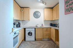 a kitchen with a washing machine and a clock on the wall at Ascot Racecourse Apartment in Ascot