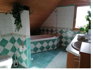 a bathroom with a bath tub and a sink at Ferienhaus Nebenan Plus in Ebern