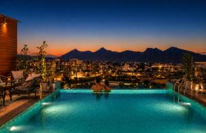 a man sitting in a swimming pool with a view of a city at Paradise Bliss Udaipur - Luxury Boutique Hotel in Udaipur