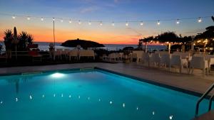 a swimming pool with a sunset in the background at Hotel Cristina in Diamante