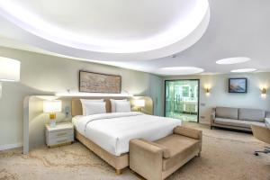 a bedroom with a large white bed and a couch at Almaty Hotel in Almaty