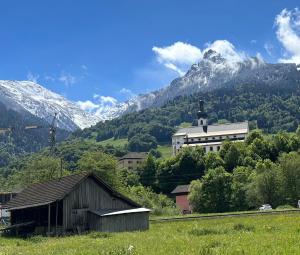 a building in a field with mountains in the background at Lieblingsplatz Alpine Lodge in Tschagguns