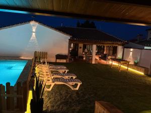 a group of lounge chairs next to a pool at night at La Casita del Tejar in Cardiel de los Montes