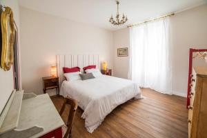 1 dormitorio con 1 cama blanca grande con almohadas rojas en Bed and Breakfast La Cordonnerie en Villandraut