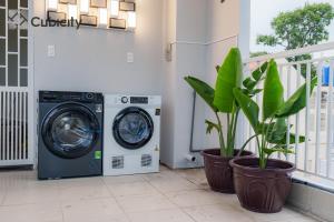 a washing machine sitting next to two potted plants at Cubicity Ton That Tung in Ho Chi Minh City