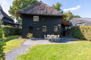 a black house with a table and chairs in the yard at De Toffe Peer Recreatie in Ruinerwold