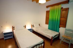 Thea House Patmos في Kámbos: سريرين في غرفة ذات ستارة خضراء