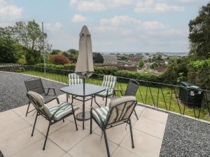 a patio with a table and chairs and an umbrella at Graig Goch in Burry Port