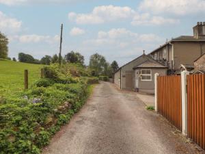 a dirt road next to a house and a fence at Little Plumtree in Milnthorpe