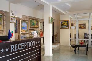 a reception area of a store with paintings on the walls at Peshev Family Hotel Nesebar in Nesebar