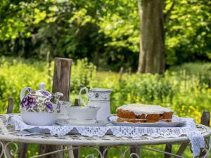 a table with a cake and tea sets on it at The Old Apple Shed cosy heated cottage in a meadow close to the charming village of Bethersden in Ashford