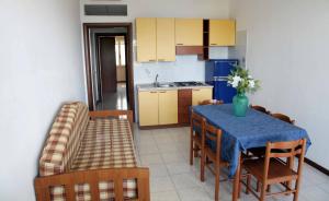 a kitchen with a table and chairs and a kitchen with yellow cabinets at Club Residence Tropea Pace in Tropea +1 photo
