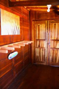 a room with wooden walls and a door with a surfboard at Lakey Peak Haven in Huu