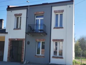 a white house with windows and a balcony at Apartament rodzinny SAKURA in Jędrzejów