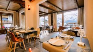 a restaurant with tables and chairs and a large window at Hotel & Spa Merilys in Méribel