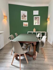 a dining room table with chairs and a green wall at Spacious, bright and comfortable bedrooms in Lannemezan