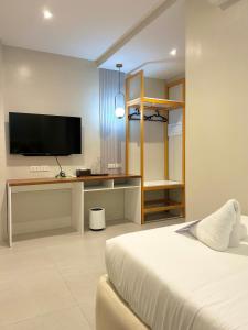 a bedroom with a bed and a desk with a television at Olive's Suites in Kalibo