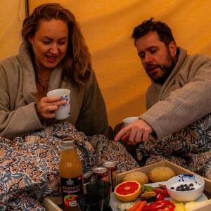 a man and woman sitting at a table with food at Fyn Glamping in Nyborg