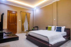 a bedroom with a bed and a desk and a television at Urbanview TWH Costel near Stadion Maguwoharjo Yogyakarta in Yogyakarta