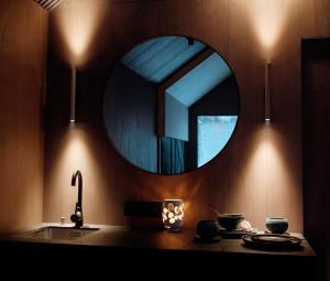 a bathroom with a round mirror and a sink at refleXions in Kabakelis +3 photos