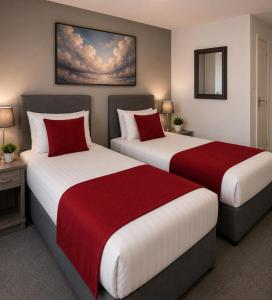 two beds in a hotel room with red pillows at Saram Lodge Dudley in Dudley