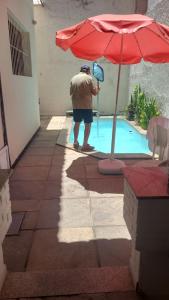 a man standing next to a pool with an umbrella at Pousada Icaraí Inn in Niterói
