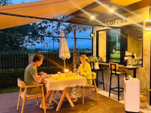 two people sitting at a table under an umbrella at Tuyo Homestay in Ban Pang Kiang