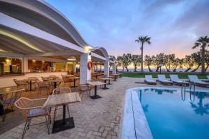 a resort with a pool and tables and chairs at Malia Bay Beach Hotel & Bungalows in Malia