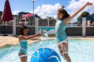 two young girls playing in a fountain in a pool at Camping RCN Port l'Epine in Trélévern