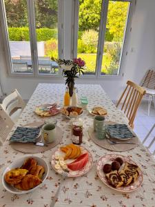 a table with plates of breakfast food on it at La Pause Normande - Bed & Breakfast in Bayeux