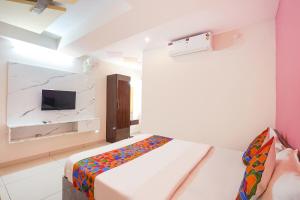a bedroom with a bed and a tv on a wall at FabHotel Saanidhya Comforts - Tumkur Road in Kunigal