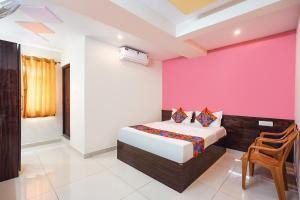 a bedroom with a bed and a pink wall at FabHotel Saanidhya Comforts - Tumkur Road in Kunigal