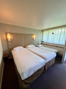 a hotel room with two beds and a window at Campanile Chambéry in Chambéry