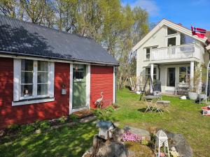 a red house and a white house with a yard at Hammergaarden Stabbursstua - Heritage Loft Stay in Sortland